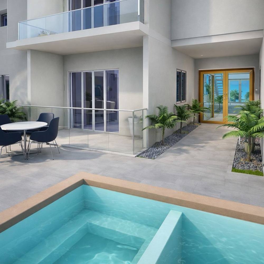 Patio interior y acceso de Residencias Sofía I con palmeras y acabados en porcelanato